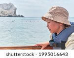 Small photo of An Asian boy in panama, life jacket floating on pleasure boat on the sea and getting seasick.