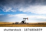 An industrial oil pump jack working on farm land under a morning sky in Rocky View County Alberta Canada.