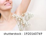 Young woman holding her hands up and showing armpits with gypsophila in her hand, armpits smooth transparent skin. The girl shows a clean armpit. Beauty portrait. Hair removal and depilation.