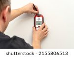 Small photo of Man using stud finder to locate framing studs located behind the walling surface. Using a wall scanner to identify hidden electrical wiring. Space for text.