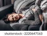 Small photo of Depressed young caucasian woman lying sofa with her arms around herself, unhappy caucasian female brunette suffering from insomnia depression, psychological problem, concept impotence, asthenia