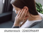 Small photo of Tinnitus concept. Close up up of sick young caucasian female touch plug ear suffer from noisy disturbing sound sitting on sofa at home. Annoyed millennial lady having earache, hearing problems