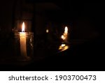 Small photo of Candles on kitchen counter during power outage. 2 candles are inside a mason jar. Pitch black room except the candle lights. Selective focus on first candle with bokeh lights in the back.