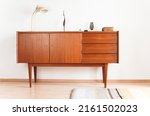 a vintage 60s mid century sideboard cupboard made out of teak wood in denmark standing in the living room danish design high quality decorated furnished 20s lamp