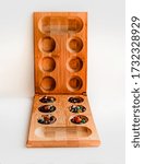 Small photo of board game from bamboo and natural stones kalah / mankala on a white background