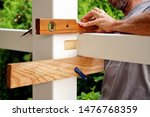 Small photo of carpentry joints. Wood post, rabbet joint. Mounting the carport. carpenter using a spirit level to connect a spruce wooden beam for Carport outdoor construction. Woodworking and carpentry concept.
