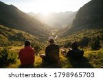 Group of young men sitting on the grass watching the sunset on top of a valley in Pyrenees