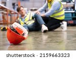 Small photo of Selective focus at hat, Men worker feel painful and hurt from the accident that happen inside of industrial factory while his co-worker come to give emergency assistance and help. Accident in factory.