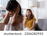 Small photo of Indoor shot of young Asian girl crying and cover her ear with hands and feel sad while get scold and shout with angry from her angry mother. Child abuse that can cause a problem for children.