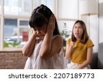 Small photo of Indoor shot of young Asian girl crying and cover her ear with hands and feel sad while get scold and shout with angry from her angry mother. Child abuse that can cause a problem for children.