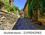 Small photo of Picturesque alley with houses made of stone and pots with flowers in the medieval village of Beget, Girona, Catalonia.