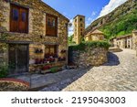 Small photo of Picturesque alley with houses full of flowers and main square with Romanesque church in the mountain village of Beget, Catalonia.