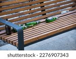 Small photo of Moscow, Russia - March 2023: Empty glass beer bottles on bench in park. Urban alcoholism concept. Social issues of alcohol and immoral behaviour
