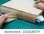 Small photo of Book Repair A book teardown repairer, repairing the spine of a book cover., Indentification problems, Restoration, Repairing damaged book covers, Dismantle damaged parts to repair.