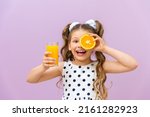 A little girl holds orange...