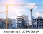 Small photo of A crane and a building under construction against a blue sky background. Builders work on large construction sites, and there are many cranes working in the field of new construction.