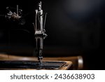 Small photo of An old sewing machine stands on the table at home ready to work and sew. Classic retro style manual sewing machine ready for sewing work. The machine is old style made of metal with floral patterns