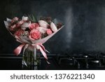 Small photo of stillish floral bouquet of ranunculus fnd roses heart shape standing near the hob