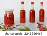 Small photo of Hot sauce made from fermented fresh Tabasco chili peppers. Jar with fermentation process and ready sauce on a table.