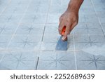 Tiler laying the ceramic tile on the floor. Grouting ceramic tiles. Professional worker makes renovation. Construction. Hands of the tiler. Home renovation and building new house
