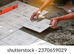 Small photo of Floor tiles installation. Ceramic tiles and tools for tiler. Home improvement, renovation - ceramic tile floor adhesive, trowel with mortar, level.