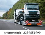 Small photo of A side view of the towing truck with a brand-new commercial vehicle for cargo shipping. Emergency roadside assistance. Vehicle Mechanical Problem on the Road. Warranty case. Bill of Loading Manifest.