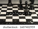 Small photo of The concept of Transfix represented by black letter tiles with chessboard background