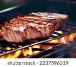 Small photo of Juicy bloody steak on the grill against the background of flames. Shallow depth of field