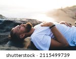 Small photo of Bearded man with closed eyes lysing and resting during pastime for pranayama breathing in nature environment, calm male yogi feeling mindfulness enlightenment during holistic healing and retreat