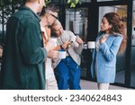 Small photo of Group of multiracial colleagues with anonymous coworker gathered around during coffee break and having pep talk while male employee showing at mug and pointing finger while passing time in office