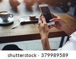 Close up of women's hands holding cell telephone with blank copy space scree for your advertising text message or promotional content, hipster girl watching video on mobile phone during coffee break 