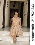 Small photo of ISLAMABAD, PAKISTAN - JANUARY 13, 2024 :Young beautiful classy girl sitting on the floor in short frock dress in comfortable home interior