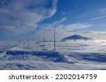 Winter scenery of tourist trail with frozen stakes in mountains in sunny day. Sniezka Peak in background. Karkonosze Mountains (Giant Mountains), Poland