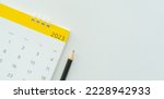 Small photo of close up white calendar 2023 month schedule with pencil to make appointment meeting or manage timetable each day lay on white background for planning work and life concept