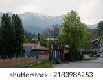 Small photo of BRAN, ROMANIA - MAY 26, 2014: Snow-covered mountains loom over Bran village, on General Traian Mosoiu street, the main road through Bran village.