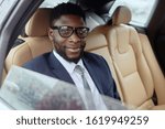 Man sits in a car and looks at the camera smiling.