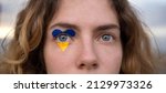Small photo of female eyes close-up with a drawn flag of Ukraine. National symbol of freedom and independence. Russian invasion of Ukraine, Stop the war. Hope and Faith