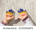 hands of a child in national clothes, painted in yellow - blue, the inscription STOP WAR. Russia's invasion of Ukraine, Children against the war. Military conflict with Russia.. Stand with Ukraine