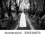Ghost covered with a white ghost sheet  on a rural path. Grainy textured image to add vintage look. 