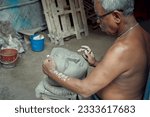 Small photo of Kumartuli, 07-09-2023: an aged artisan looking at a beautifully decorated clay face idol of Goddess Durga, as he paints with meticulous detail. Shot few months before start of Durga puja festival.