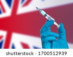  Fight against the epidemic of coronavirus in Great Britain.Doctor's hand in medical gloves with vaccine for  COVID-19 on the background of the flag Great Britain. Flu shot  in Great Britain