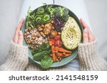 Woman holding plate with vegan or vegetarian food. Healthy plant based diet. Healthy dinner or lunch. Buddha bowl with fresh vegetables. Healthy eating