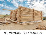 Construction site of wooden mountain house. Traditional log cabin built from wood logs on sunny summer day. Cottage house design