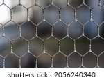 Small photo of Woven wire fence in close-up. Repeated hexes of galvanized wire. Selective focus.