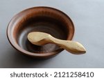 Small photo of Brown earthenware bowl and buckshot against a gray background. Empty bowl and billet for carving a wooden spoon. Selective focus.