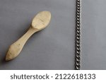 Small photo of Wooden spoon carving buckshot and chain against a gray background. Selective Focus.