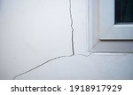 Small photo of Cracks on the wall. The crack in the cement wall at the window sill, caused by the subsidence of the ground, caused a slit at an oblique angle.
