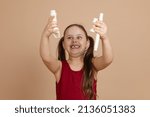 Small photo of Girl in red dress hold flute disassembled in parts over head and gloat, beige background. Learning to play woodwind musical instrument. Flute and children is concept of music education development.