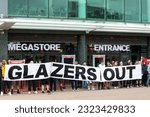 Small photo of Manchester UK. June 27, 2023. Protesters outside Manchester United football ground megastore force closure on day the club unveil their new home shirt. Banner text Glazers Out.