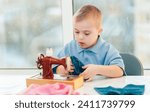 Small photo of A boy with Down syndrome sews toy things on a sewing machine. Sewing things for dolls and toys. A child with Down syndrome learns to sew things.